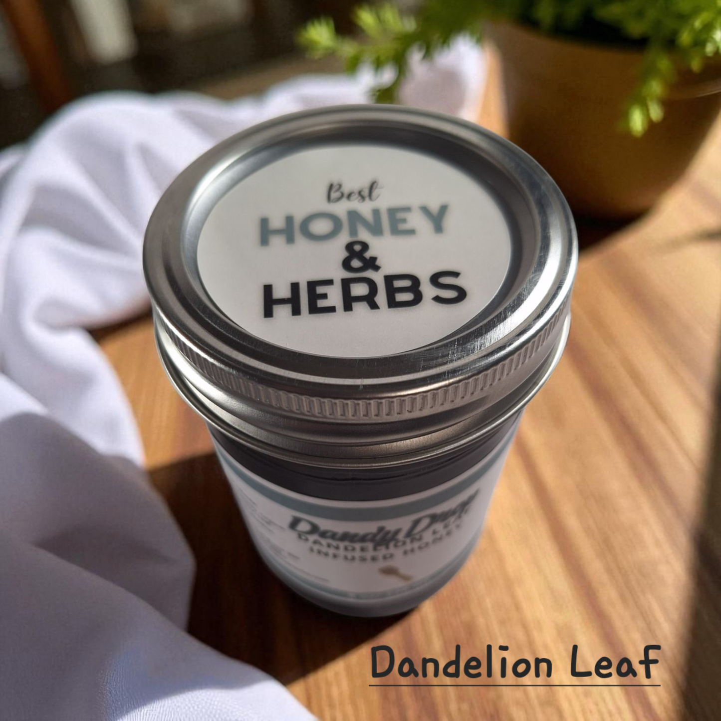 Top view of 8 oz half-pint jar of raw Dandelion Leaf Infused Honey on a wooden surface, herbal sweetener for tea, baking, and traditional wellness.