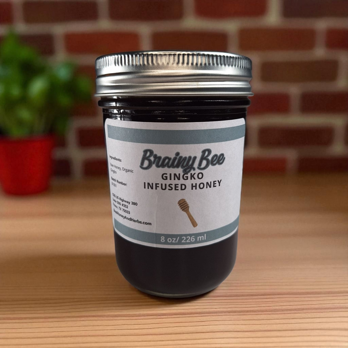 8 oz half-pint jar of raw Ginkgo Infused Honey on a wooden surface, small-batch herbal honey for tea, memory support, and healthy recipes.