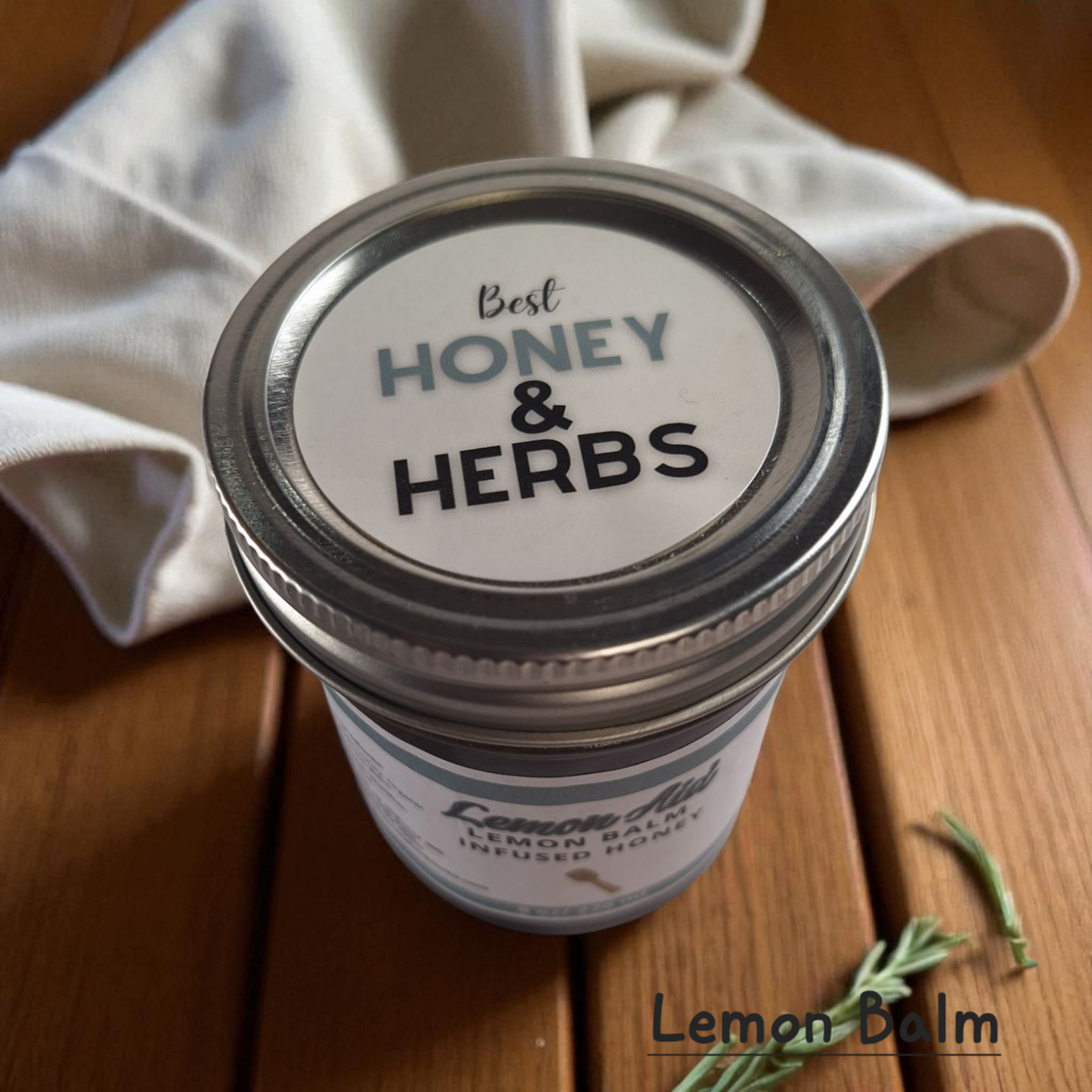 Top view of 8 oz half-pint jar of raw Lemon Balm Infused Honey on a wooden surface, citrusy herbal sweetener for tea, baking, and calming recipes.