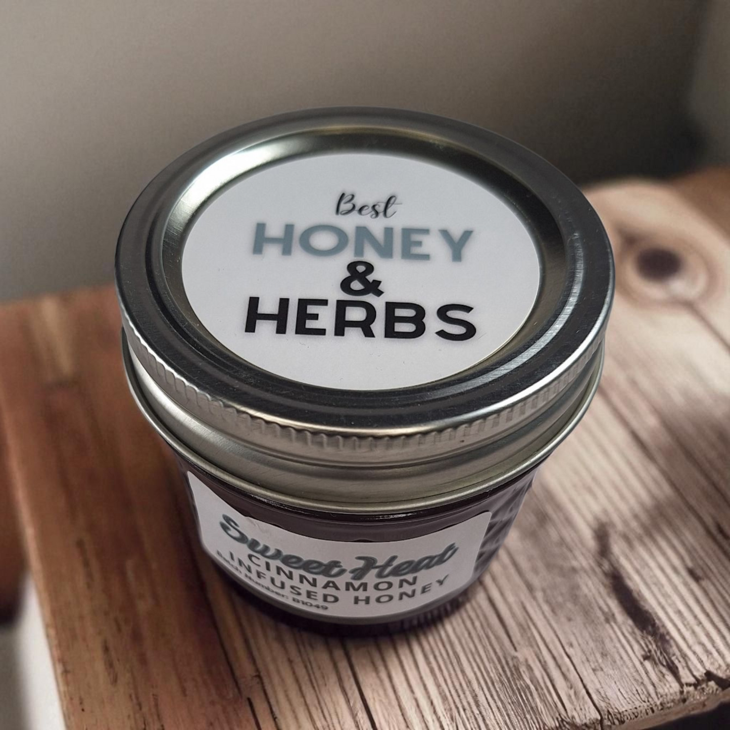 Overhead 4 oz Cinnamon Infused Honey on a textured wood tabletop; warm spiced sweetener for coffee, oatmeal, and baked desserts.