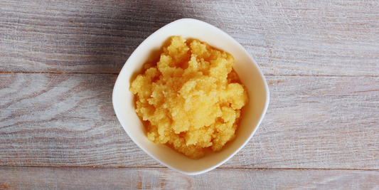 Top down view of crystallized honey n a white bowl on a wood table.