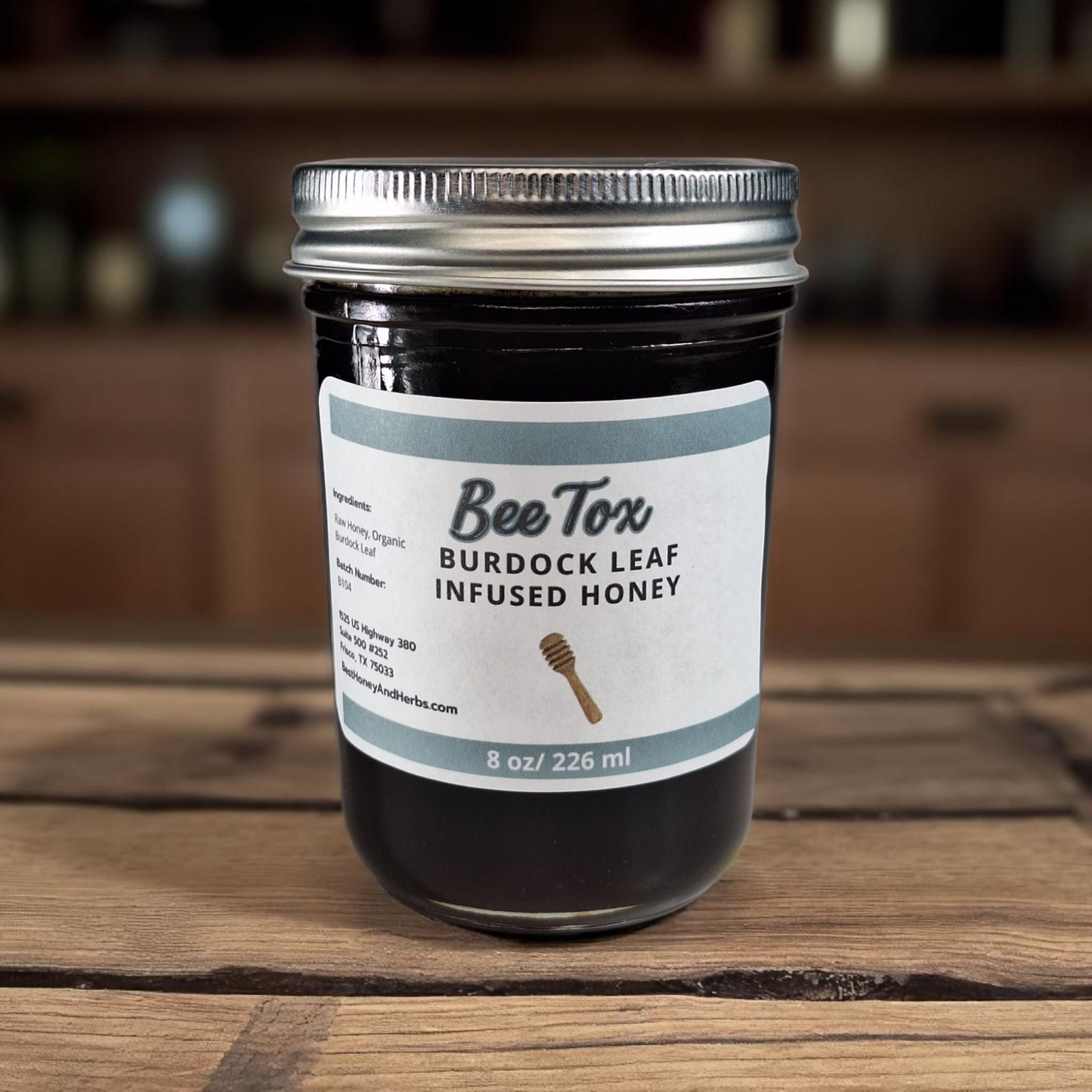 8 oz half-pint jar of raw Burdock Leaf Infused Honey on a rustic wooden surface, herbal sweetener for detox teas, tonics, and healthy recipes.