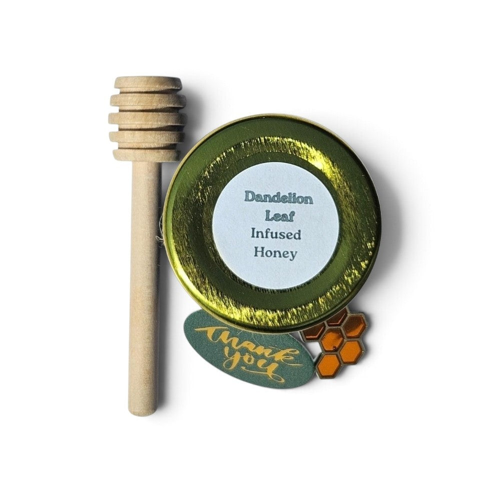 A small round tin of infused honey with a gold lid and white label reading 'Dandelion Leaf Infused Honey,' shown with a wooden honey dipper and a green 'thank you' tag on a white background.