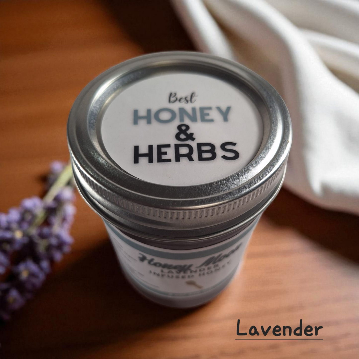 Top view of 8 oz half-pint jar of raw Lavender Infused Honey on a rustic wooden surface, floral herbal sweetener for tea, baking, and relaxing drinks.