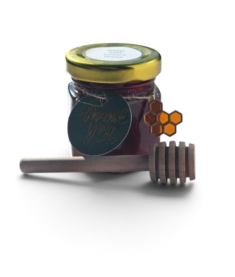 A jar of dark purple-red honey with a gold lid, a round black 'Thank You' tag, and a wooden honey dipper on a white background.