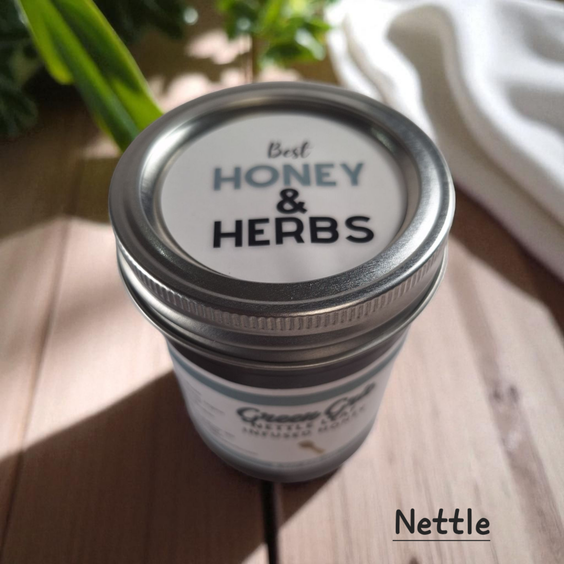 Top view of 8 oz half-pint jar of raw Nettle Leaf Infused Honey on a wooden surface, nutrient-rich herbal sweetener for tea, baking, and healthy recipes.