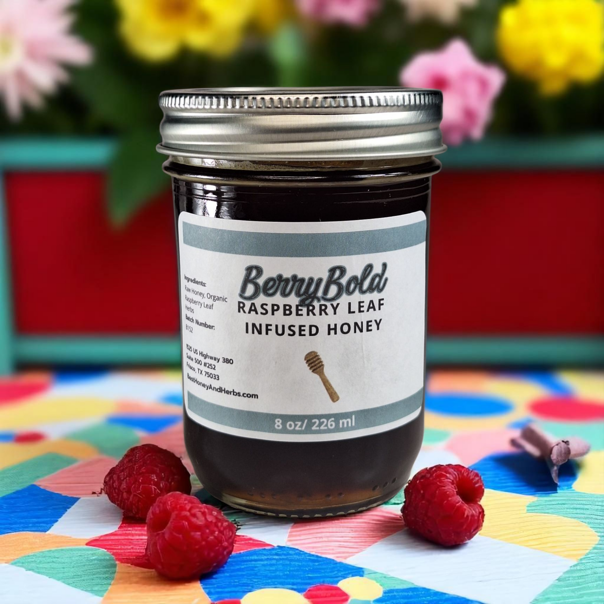 8 oz half-pint jar of raw Raspberry Infused Honey on a rustic wooden surface, fruity herbal sweetener for tea, desserts, and baking.