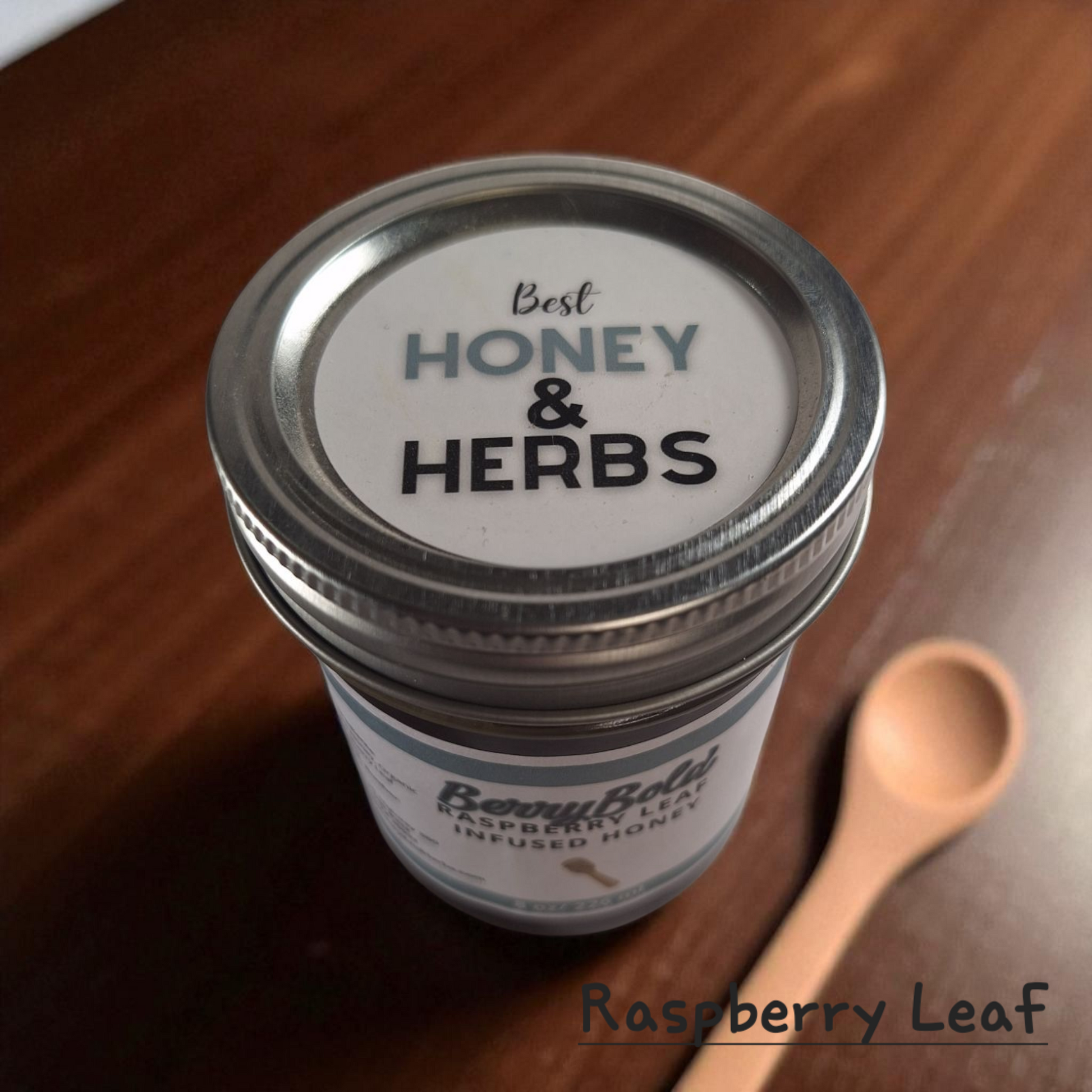 Top view of 8 oz half-pint jar of raw Raspberry Infused Honey on a rustic wooden surface, fruity herbal sweetener for tea, desserts, and baking.