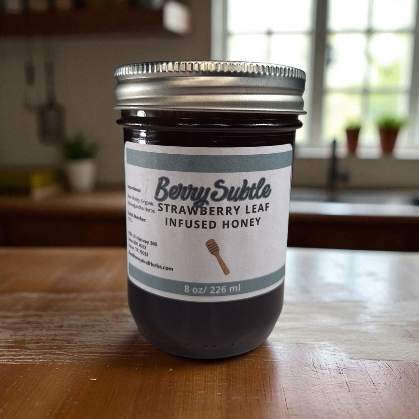 8 oz half-pint jar of raw Strawberry Leaf Infused Honey on a rustic wooden surface, mild herbal sweetener for tea, baking, and healthy recipes.