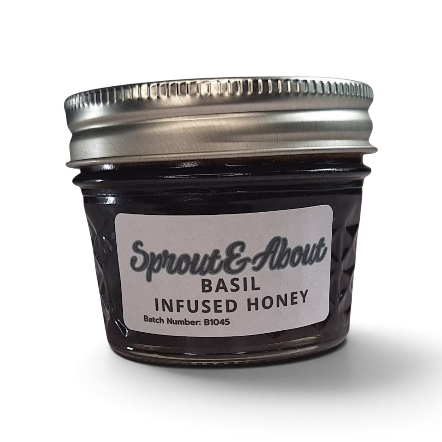 Basil infused raw honey in a small glass mason jar with a silver lid.