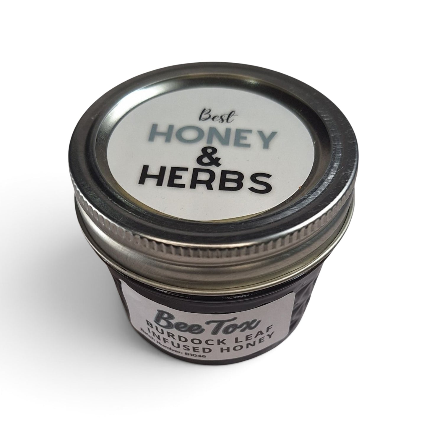 Burdock leaf infused raw honey in a small glass jar with a metal lid.