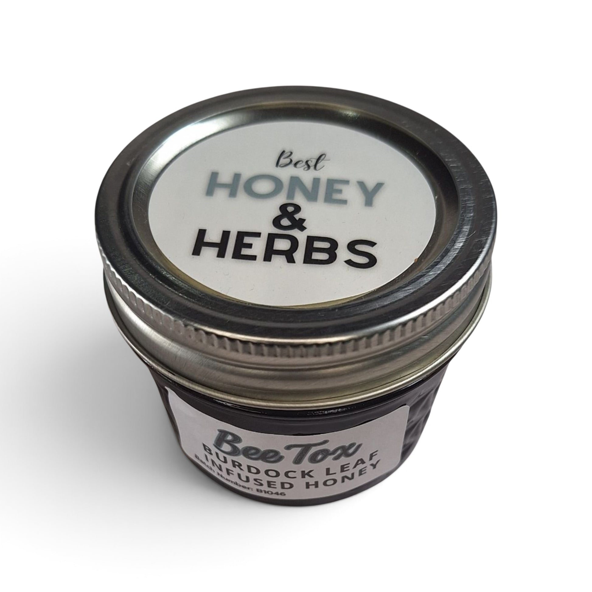 Burdock leaf infused raw honey in a small glass jar with a metal lid.