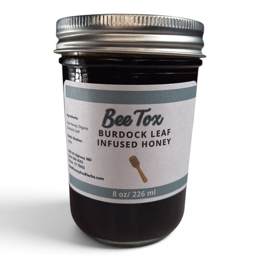 Burdock leaf infused raw honey in an 8 oz glass jar with a silver metal lid.