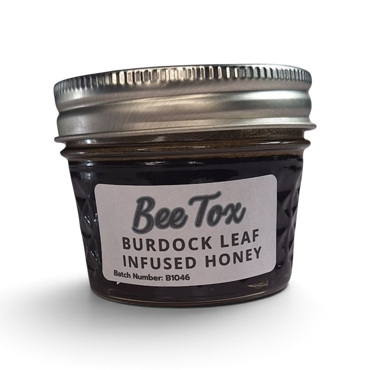Burdock leaf infused raw honey in a small glass jar with a metal lid.