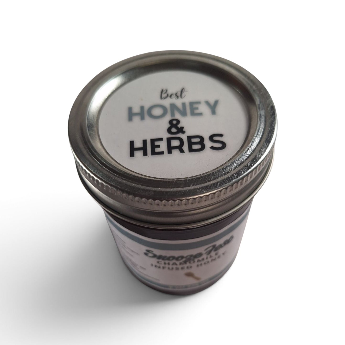 Chamomile infused raw honey in a glass jar with a metal lid, viewed from above.