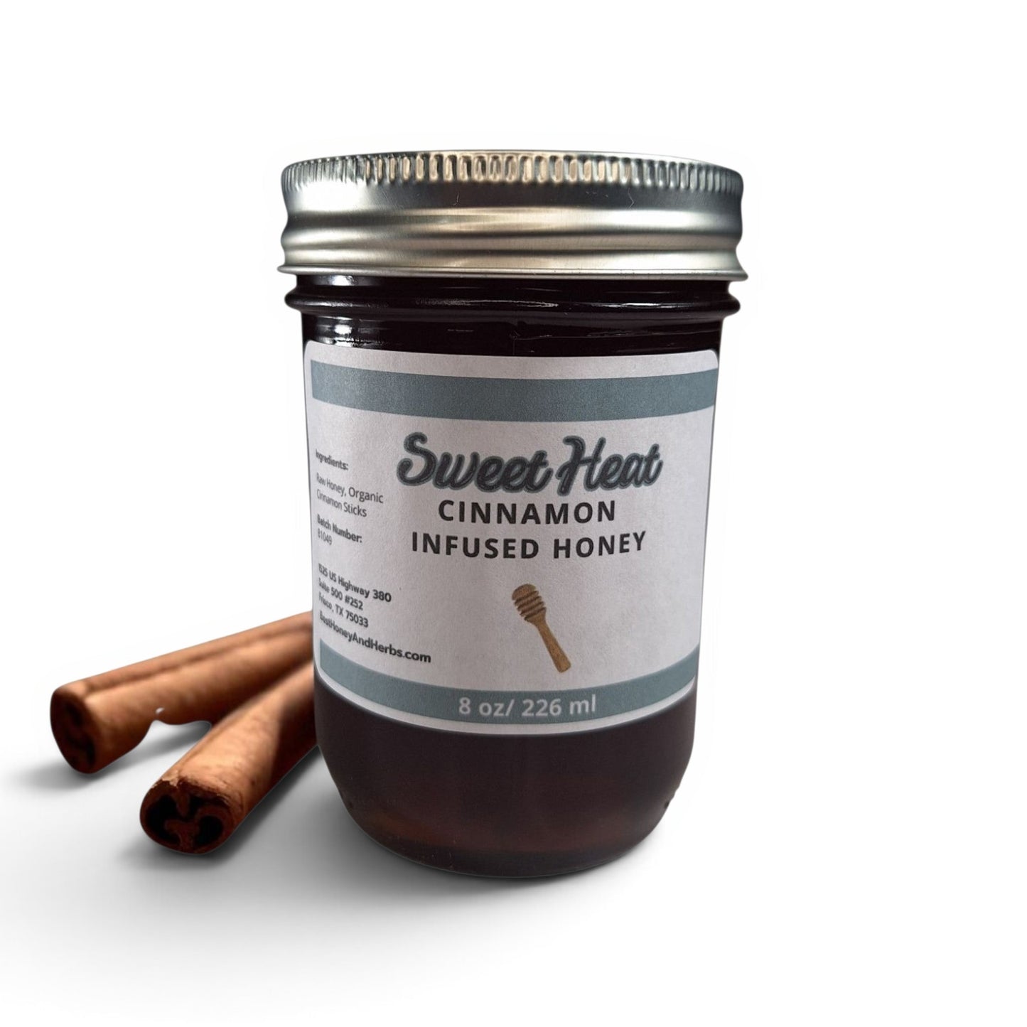  Cinnamon infused raw honey in a half pint glass jar with two cinnamon sticks on the side.