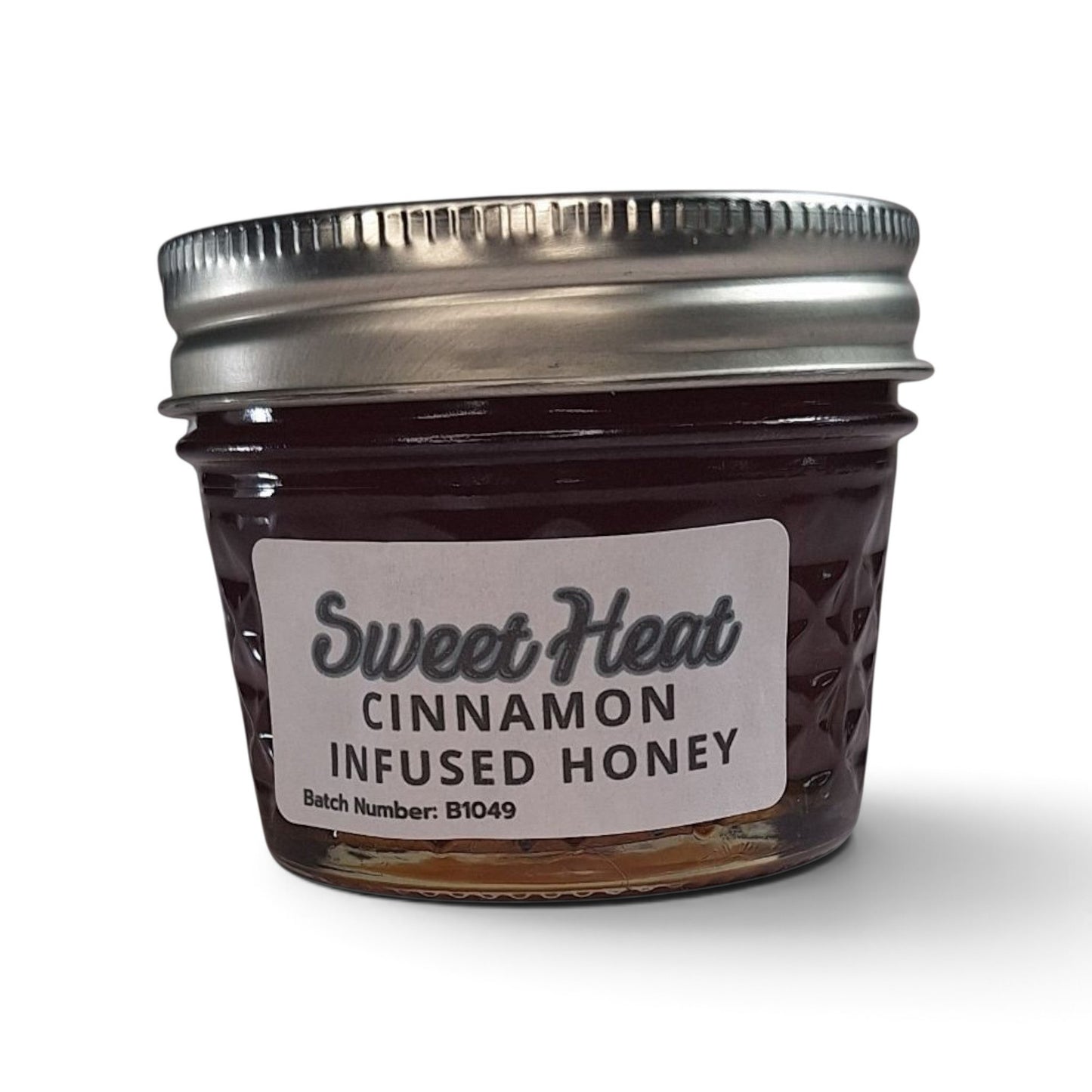 Cinnamon infused raw honey in a small glass jar with a silver metal lid.