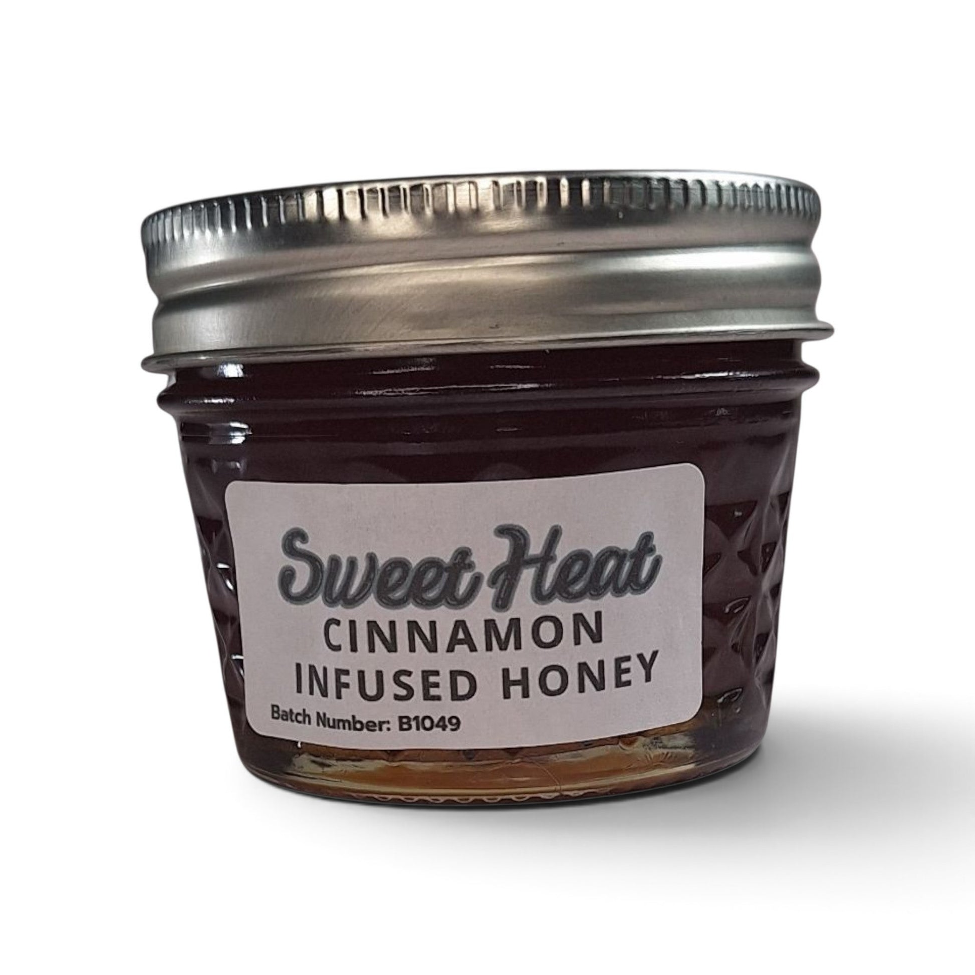Cinnamon infused raw honey in a small glass jar with a silver metal lid.