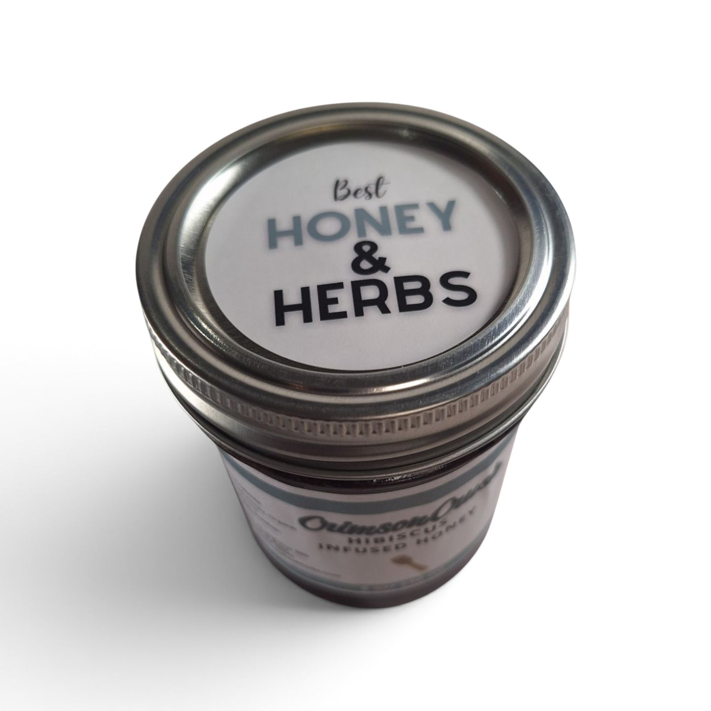 Hibiscus infused raw honey in a glass jar with a metal lid, top-down view.