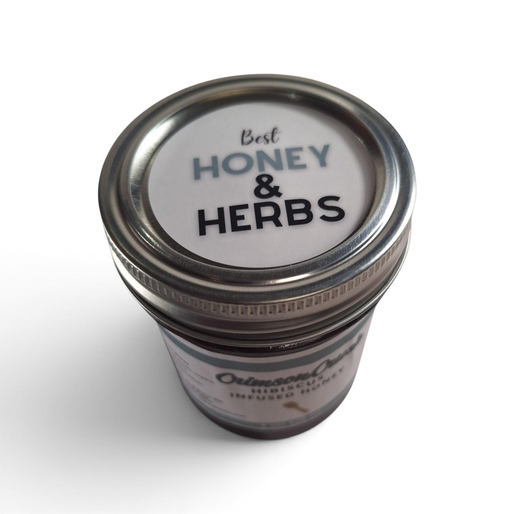 Hibiscus infused raw honey in a glass jar with a metal lid, top-down view.