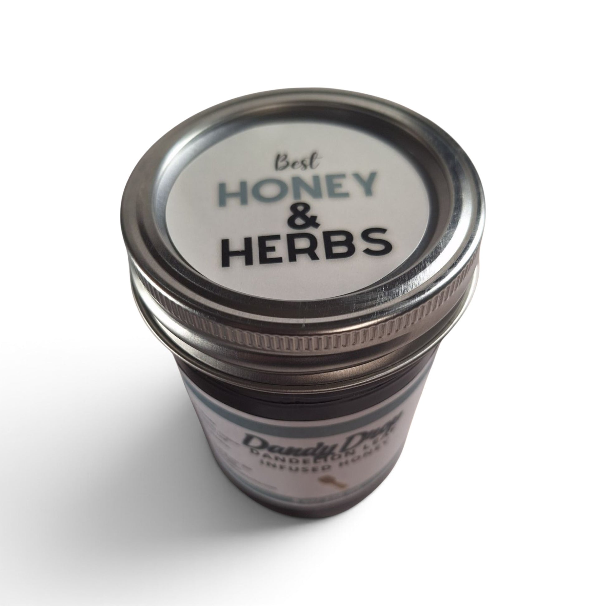  Dandelion leaf infused raw honey in a glass jar with a metal lid, top-down view.