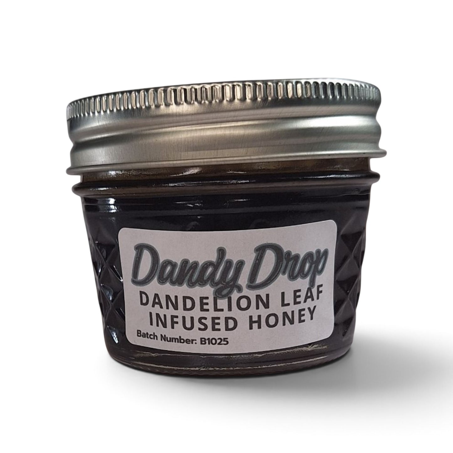  Dandelion leaf infused raw honey in a small glass jar with a silver metal lid.