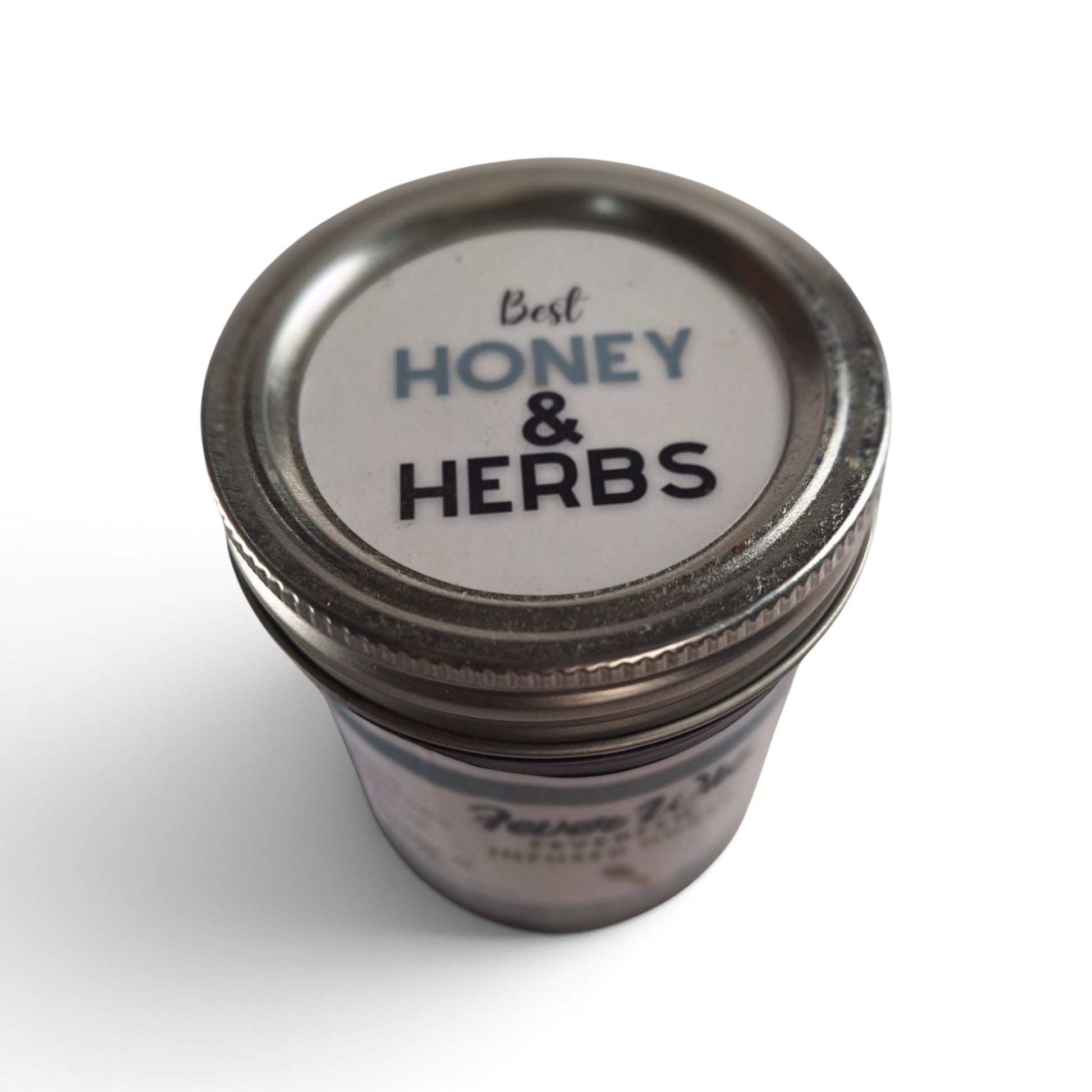  Feverfew infused raw honey in a small glass jar with a metal lid, top-down view.