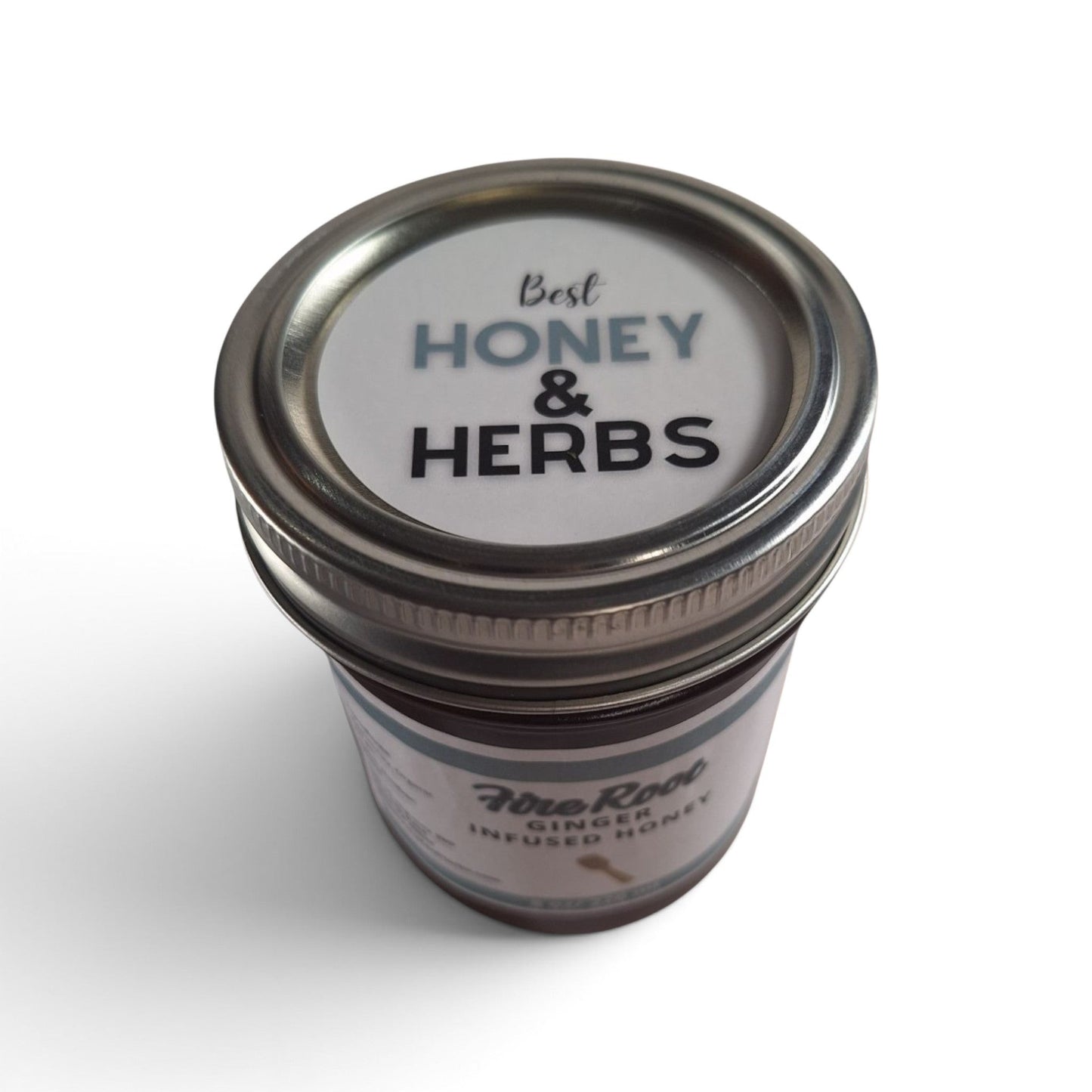 Ginger infused raw honey in a glass jar with a branded lid, viewed from above.