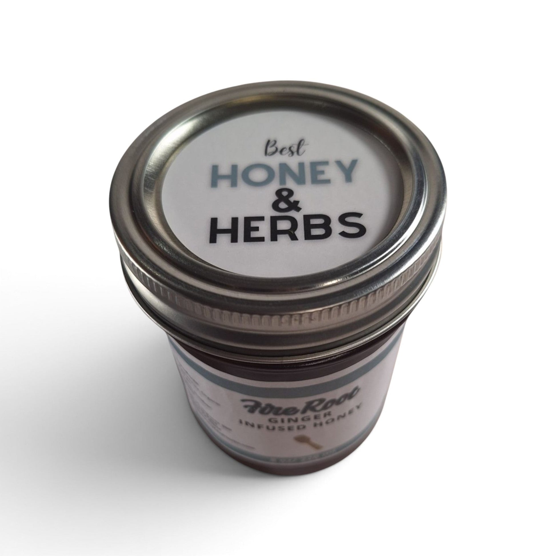 Ginger infused raw honey in a glass jar with a branded lid, viewed from above.