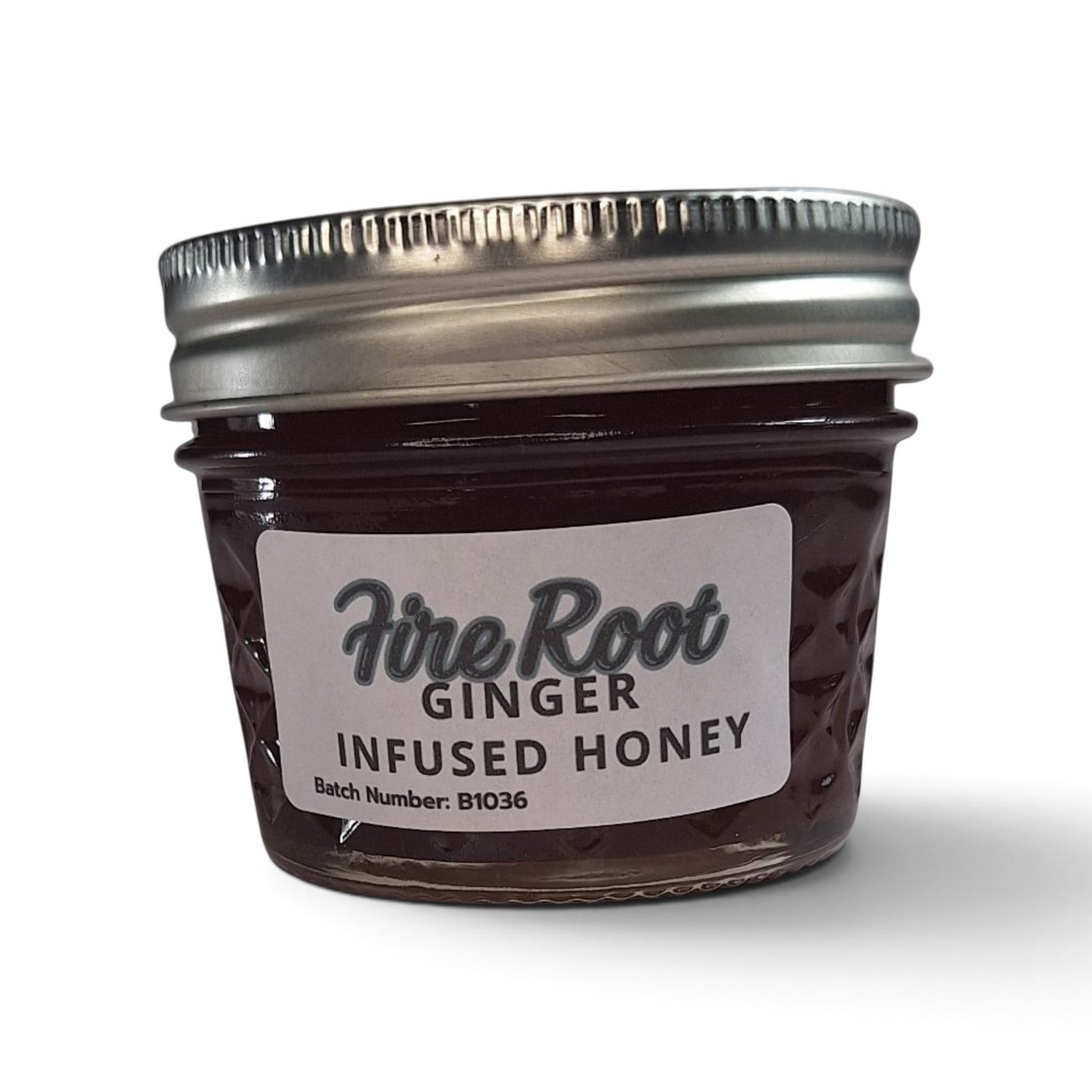 Ginger infused raw honey in a small glass mason jar with a silver metal lid.