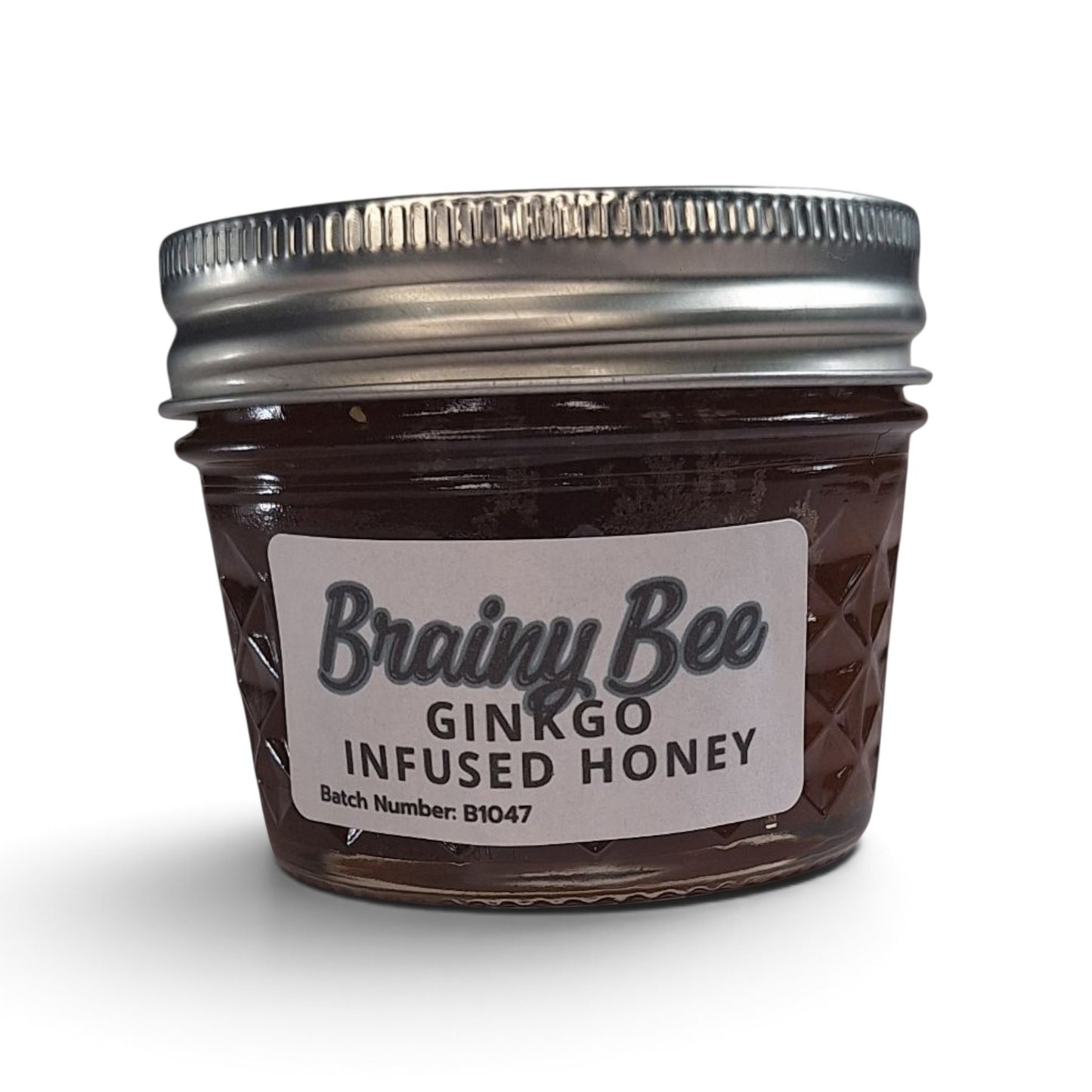 Ginkgo infused raw honey in a small glass jar with a silver metal lid.