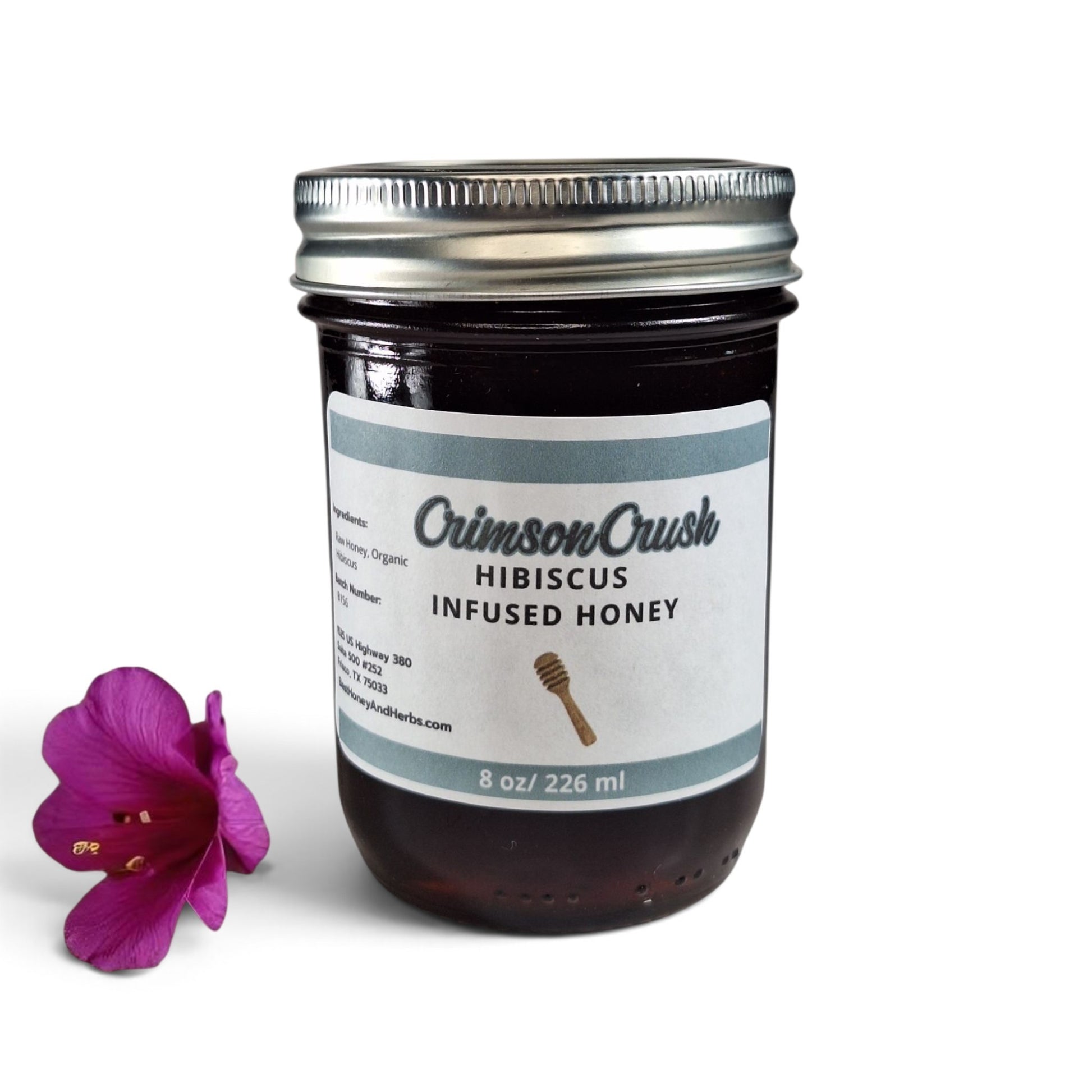  Hibiscus infused raw honey in a glass jar with a single bright pink hibiscus flower.