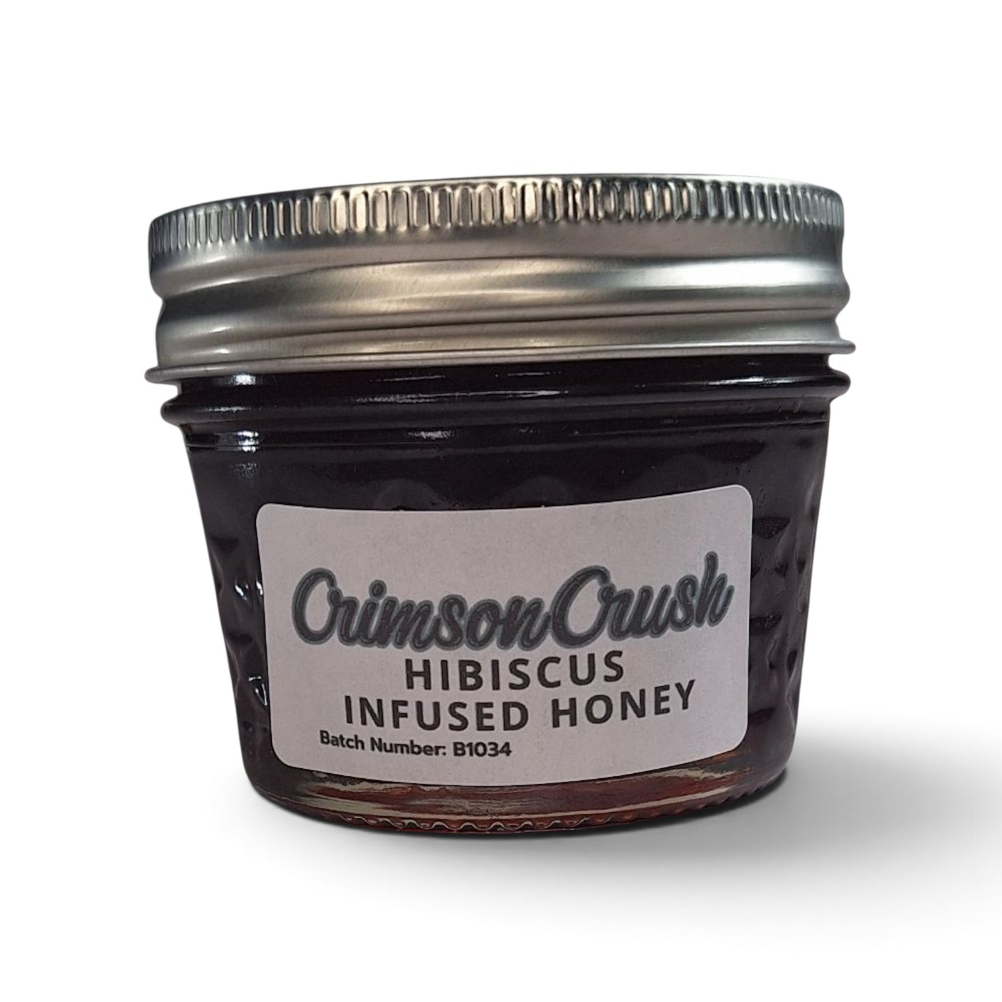 Hibiscus honey in a small glass jar with a silver lid.