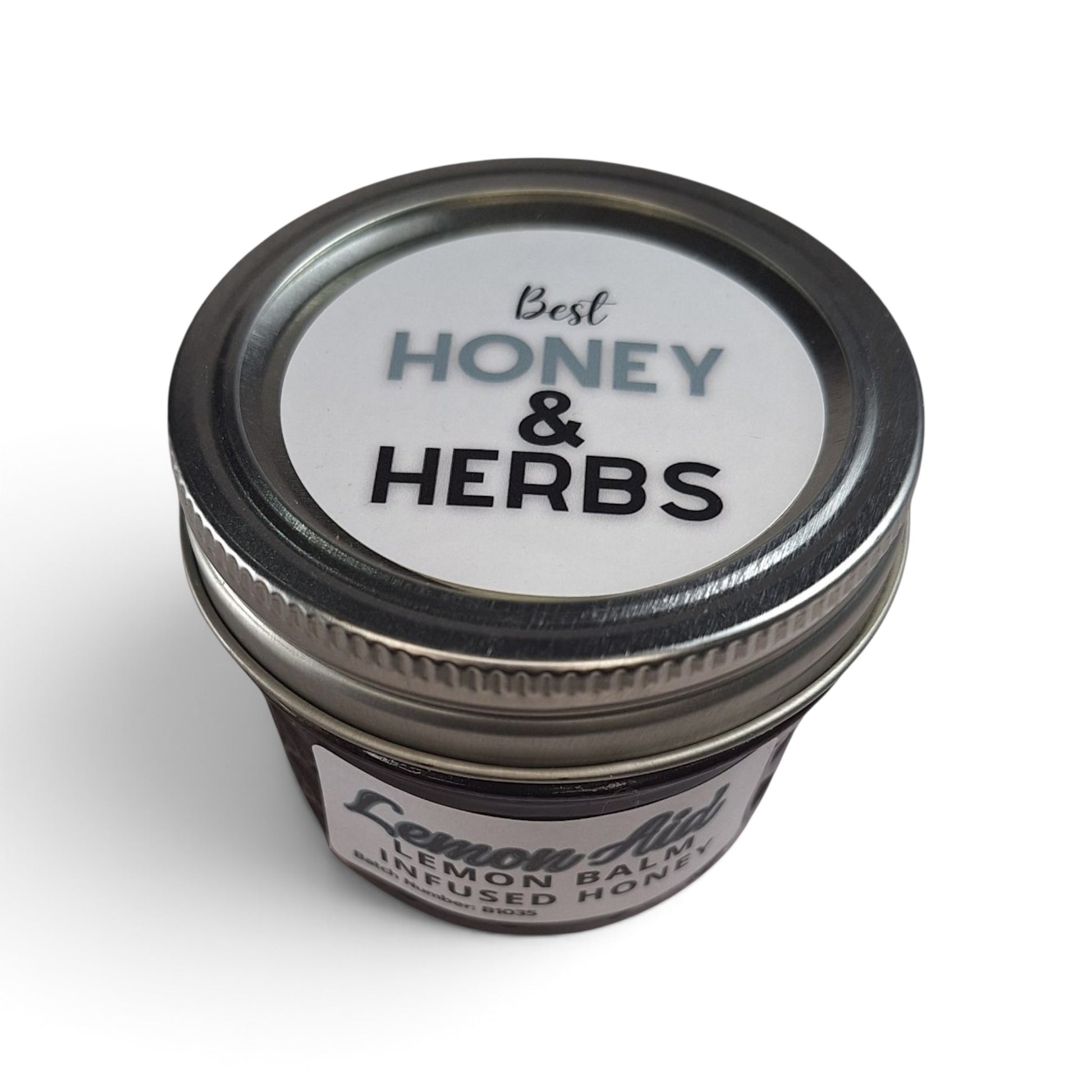 Raw honey infused with organic lemon balm in a small glass jar with a metal lid.