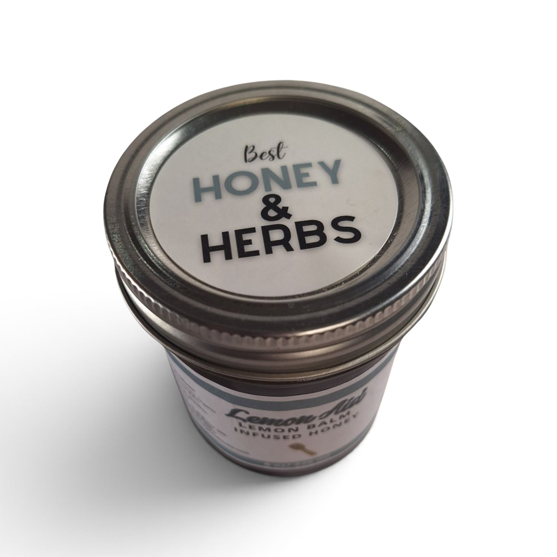 Raw honey infused with organic lemon balm in a glass jar, top-down view.