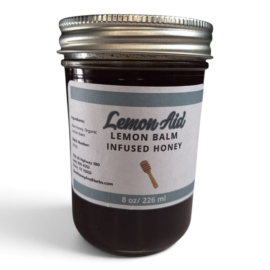 Raw honey infused with organic lemon balm in a glass jar with a metal lid.
