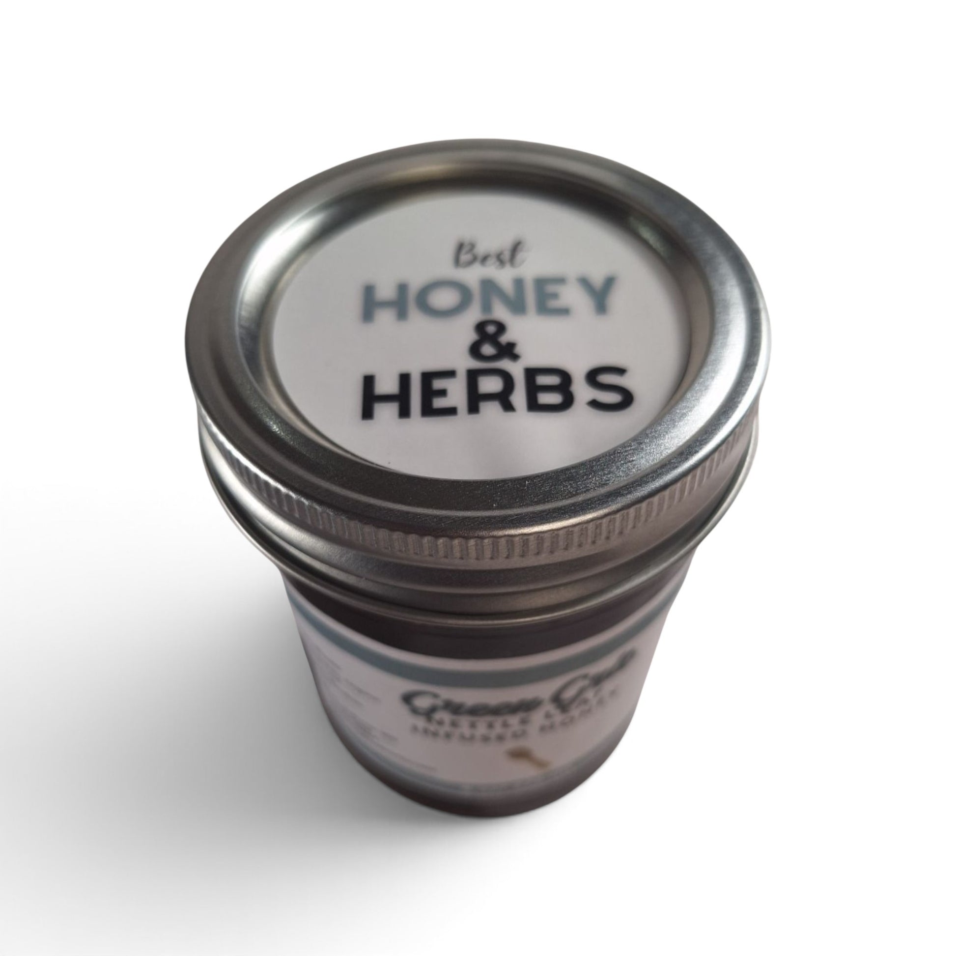  Nettle leaf infused raw honey in a glass jar with a metal lid, top-down view.