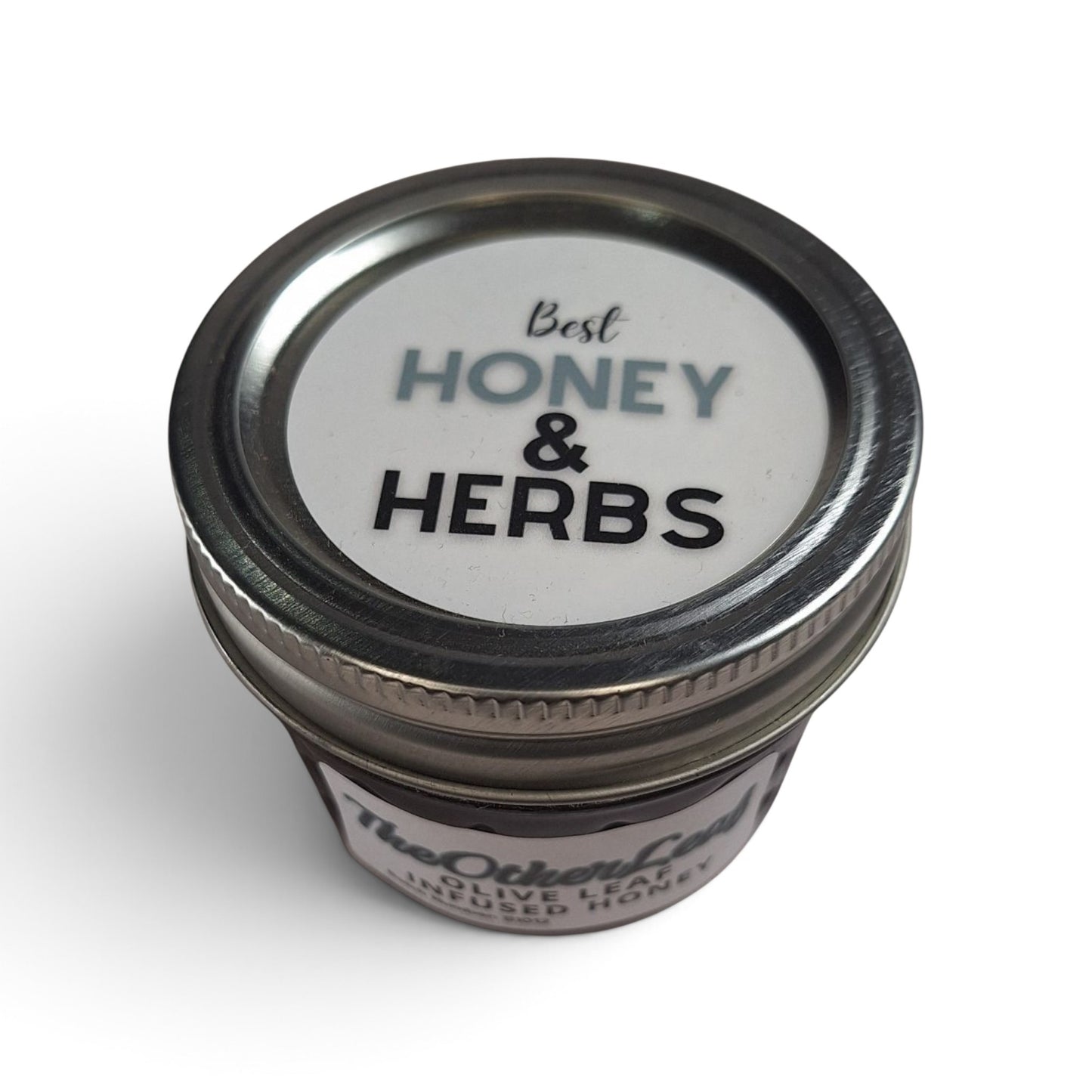 Olive leaf-infused raw honey in a small glass jar with a metal lid, viewed from above.