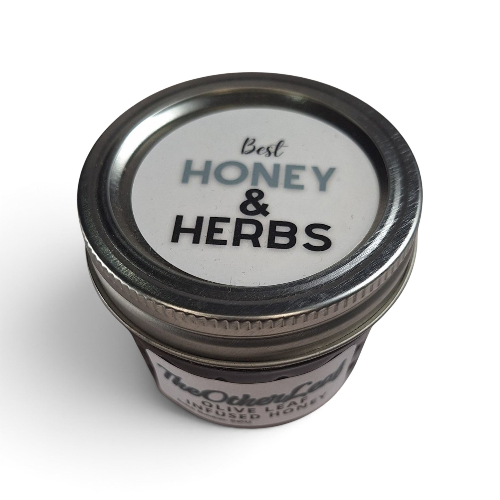 Olive leaf-infused raw honey in a small glass jar with a metal lid, viewed from above.