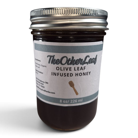 Olive leaf infused raw honey in a half pint glass jar with a silver lid.