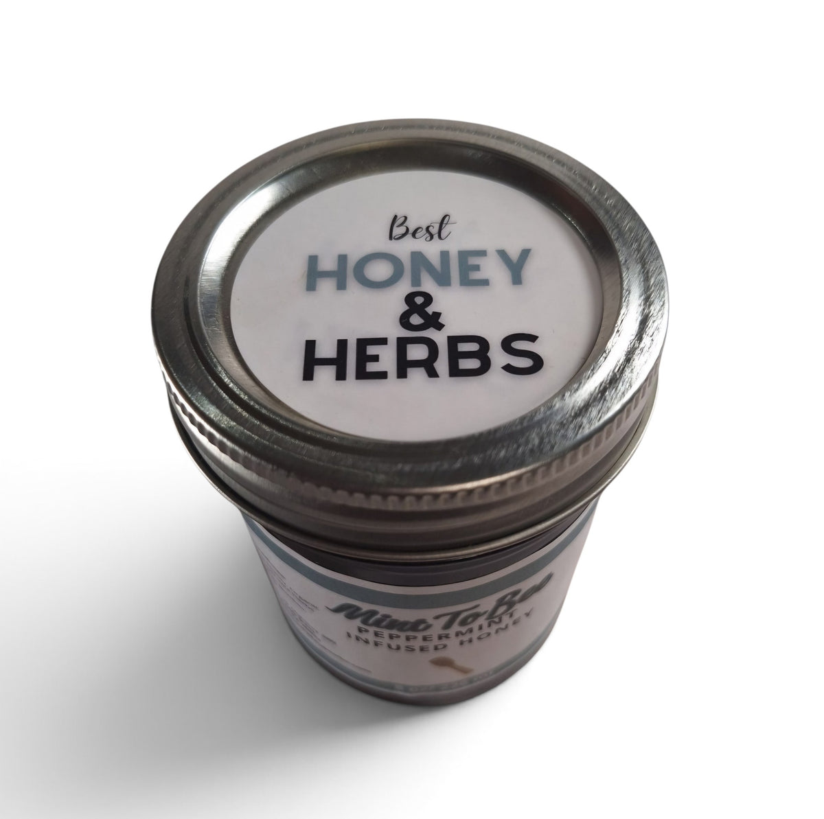 Peppermint infused raw honey in a glass jar with a metal lid, top-down view. 