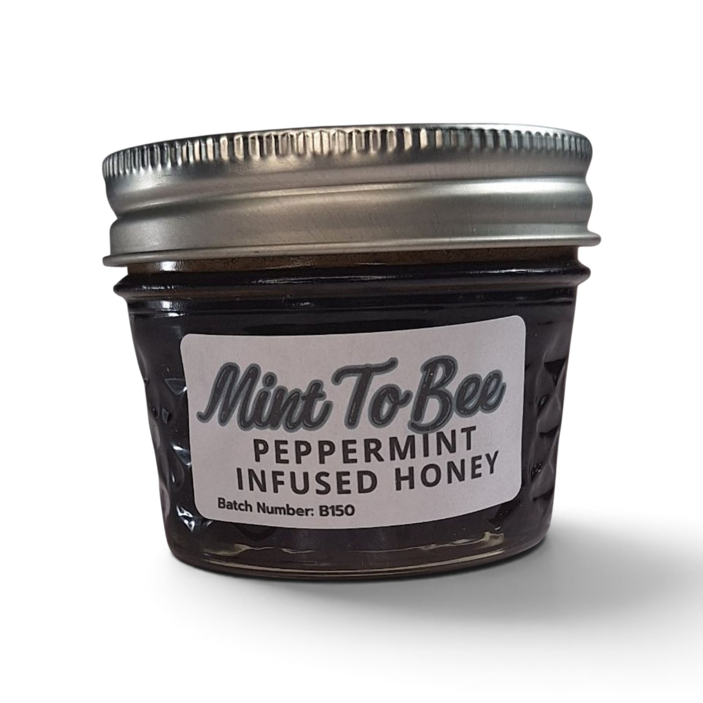  Peppermint infused raw honey in a small glass jar with a silver metal lid.