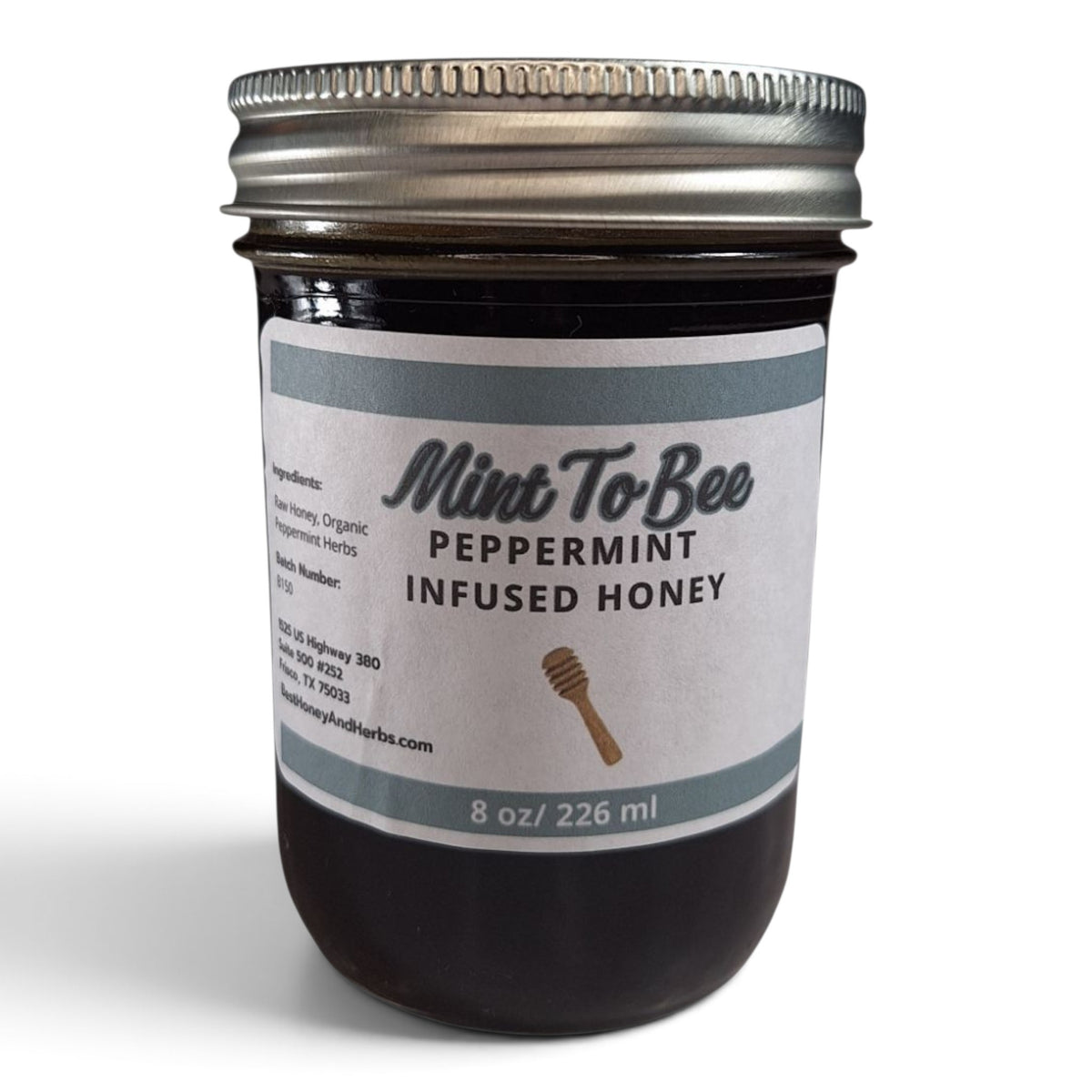 Peppermint infused raw honey in a half pint mason jar with a silver lid. 