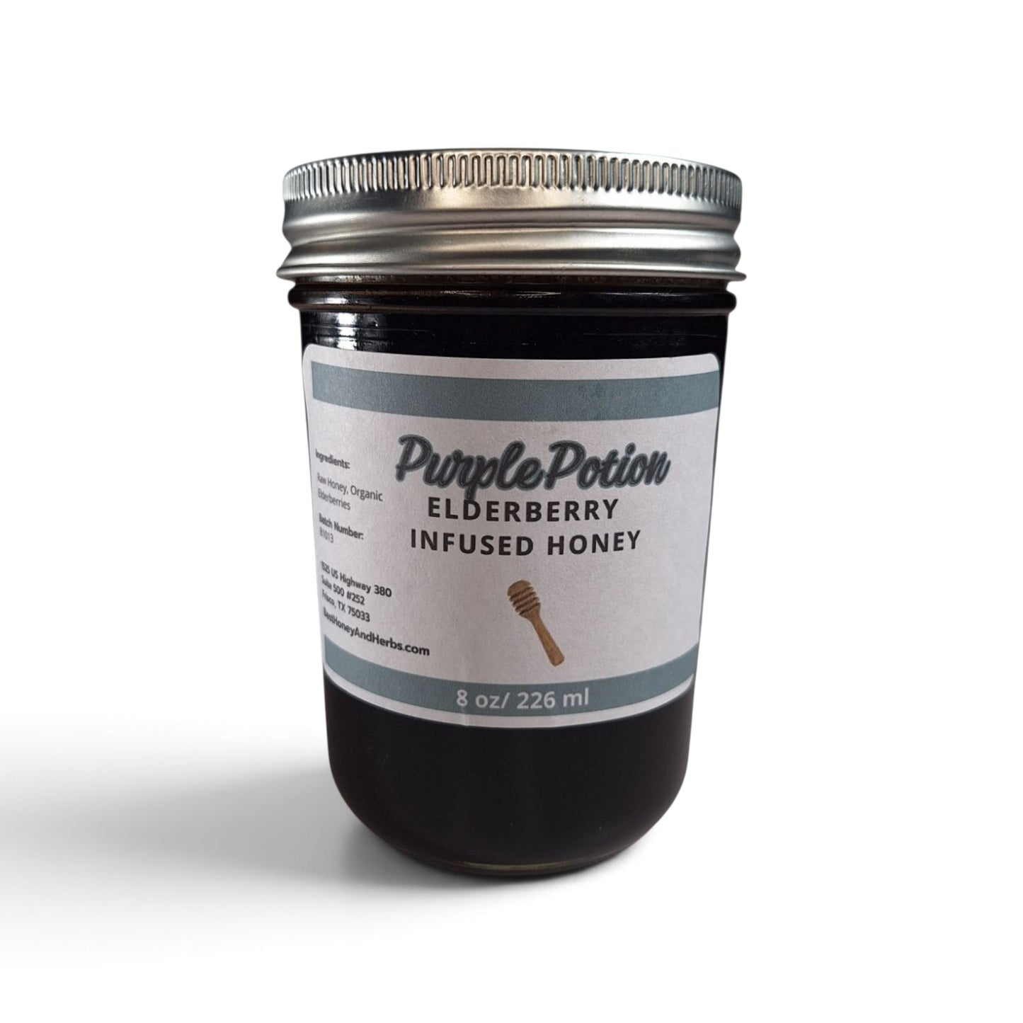  Elderberry infused  honey in a half pint glass jar on a wooden table.