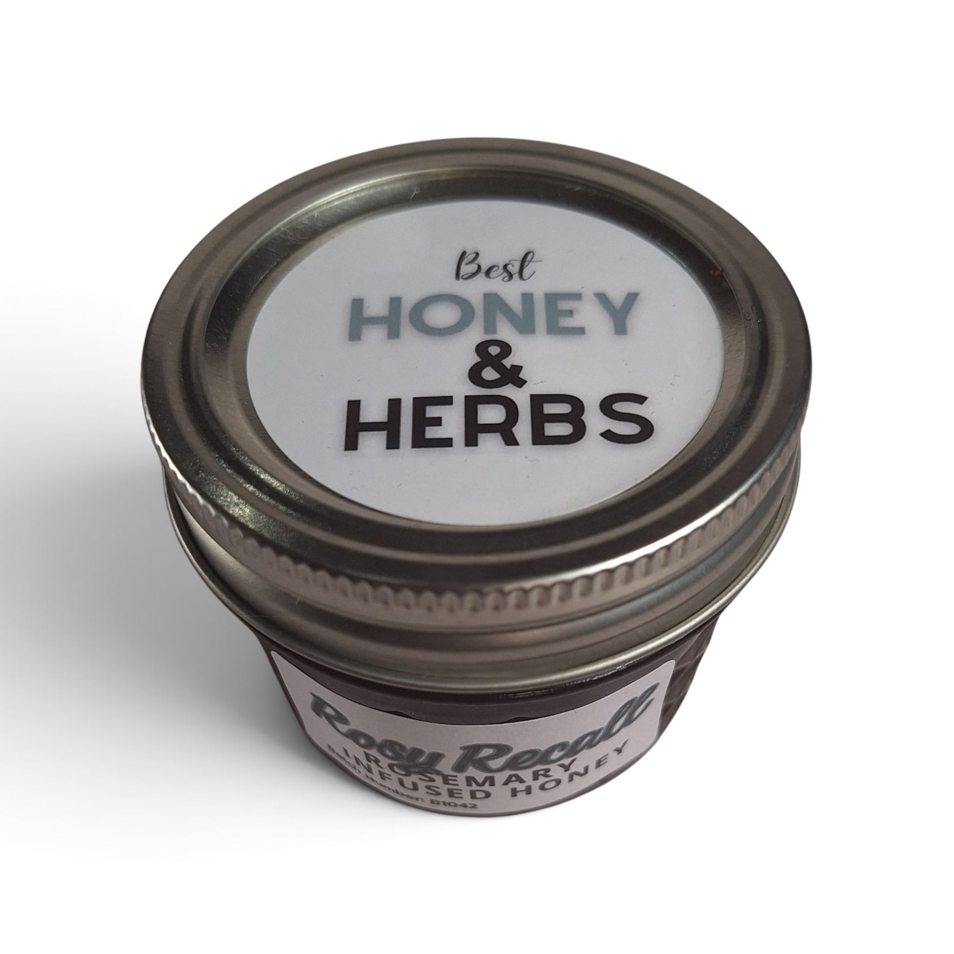  Rosemary infused raw honey in a small, mason glass jar with a silver lid, top-down view.