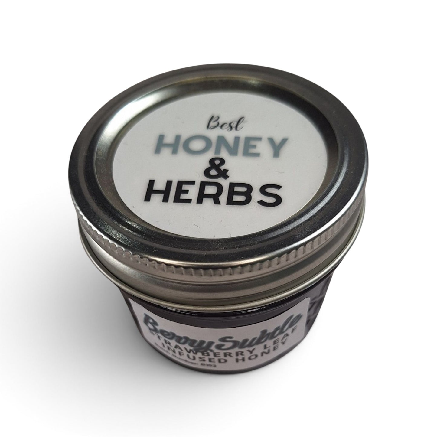  Strawberry leaf infused raw honey in a small glass jar with a metal lid.