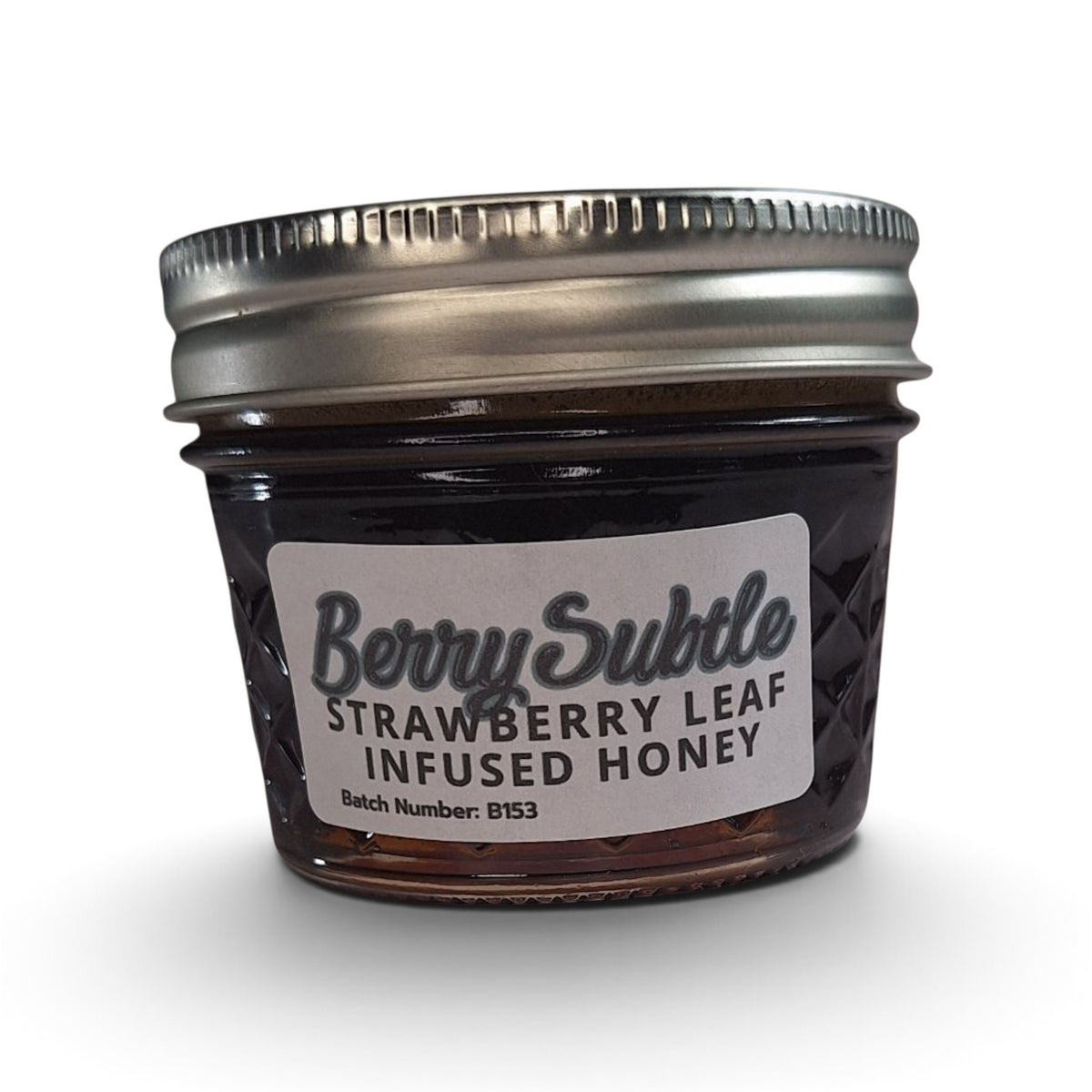  Raw honey infused with organic strawberry leaf in a small glass jar.