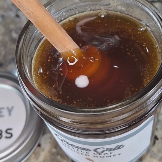  Nettle leaf infused honey slowly drizzling from a honey dipper.