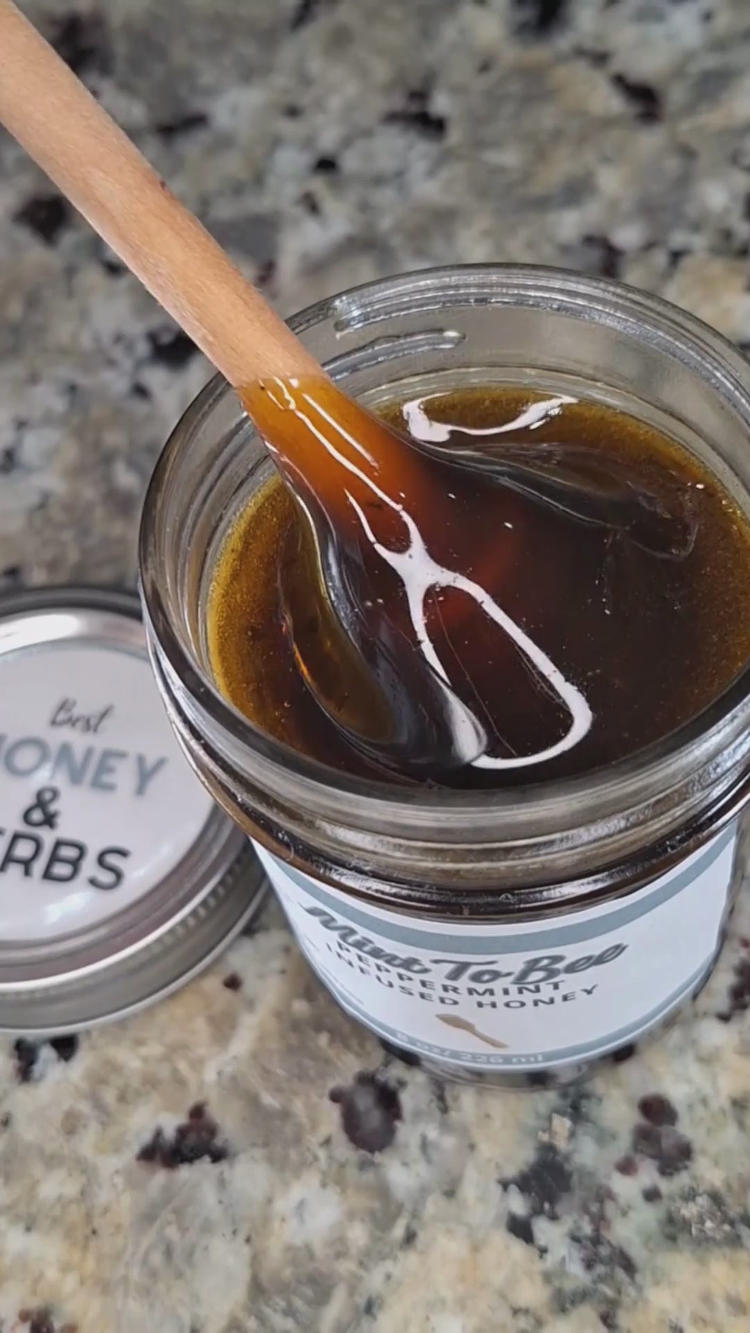Peppermint leaf infused honey slowly drizzling from a honey dipper.