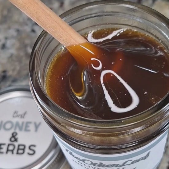  Olive leaf infused honey slowly drizzling from a honey dipper.